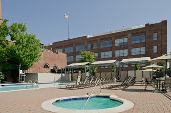 A swimming pool with chairs and a building in the background